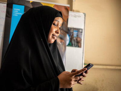Photo: WFP/Ismail Taxta Hani Mohamed (24) uses her mobile phone to order food from an online E-shop at a WFP food distribution Centre at K4 area in Mogadishu.