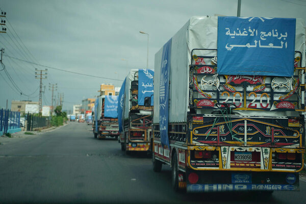 WFP trucks travel along an urban road, transporting food assistance.