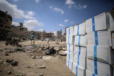 People walk among the ruins of Khan Younis to reach the local bakery that with support from the World Food Programme has been able to start operating again