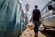 A man carries bags of pita bread past a WFP car in Gaza. Photo: WFP/Maxime Le Lijour