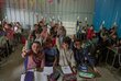 Children in a classroom raise hands that hold small packages of fortified snacks. Photo: WFP/Jaber Badwan
