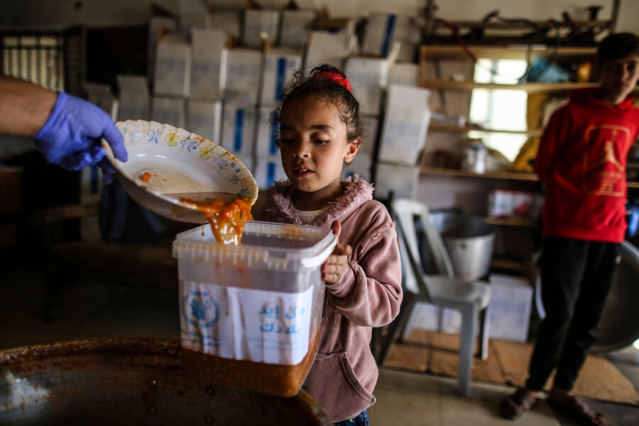 A little girl receives WFP food in Deir Albalah, in central Gaza. Famine is imminent in parts of the enclave however, as humanitarian aid piles up on its borders due to access constraints. Photo: WFP/Ali Jadallah&nbsp;