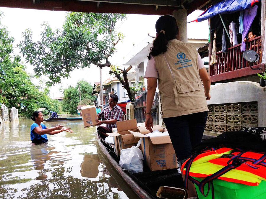 A box of food assistance is handed to a woman waist-deep in waters in a flooded part of Myanmar