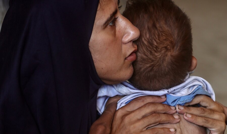 A woman in a dark veil holds a skinny little boy. Photo: WFP/Ali Jadallah