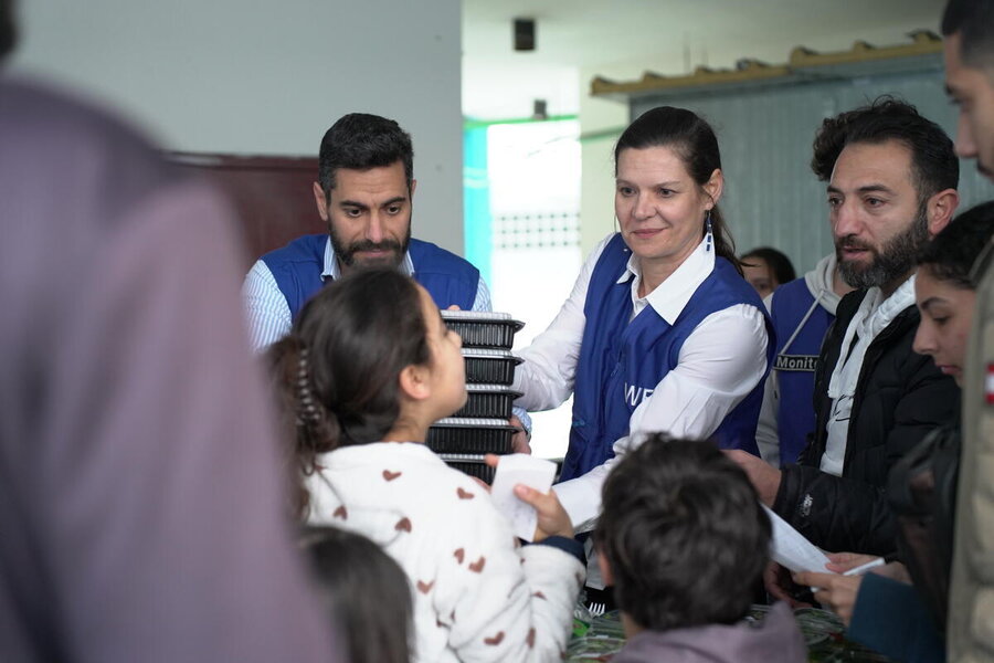 Staff in blue WFP vests deliver meals to people. Photo: WFP/Khadija Dia