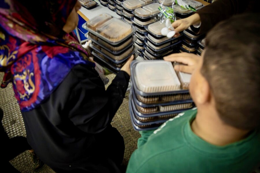 Conflict-displaced people collect plastic containers of WFP's hot meals at a Beirut shelter. Photo: WFP/Marco Frattini