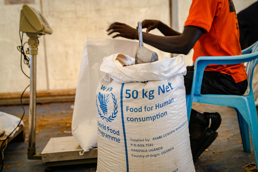 A large white sack of WFP food in the foreground, with a worker in an orange T-shirt in the background. Photo: WFP/Daisy Masembe