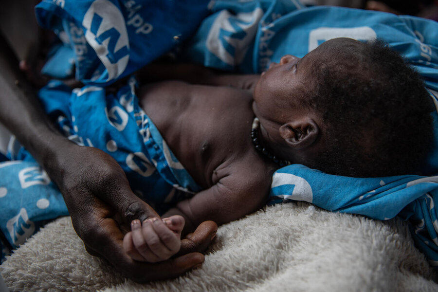 A woman holds the hand of a tiny baby wrapped in a blue blanket. Photo: WFP/Gabriela Vivacqua