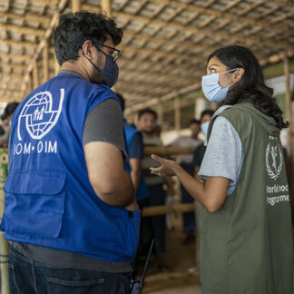 Two staffs who are wearing WFP and IOM vests are working together