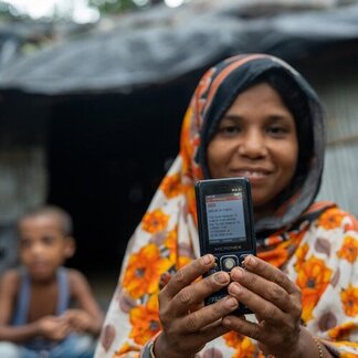 A girl holding a phone in her hand facing the camera 