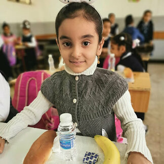 Girl in a classroom with her school meal provided by WFP
